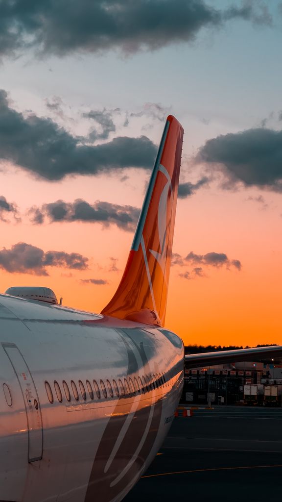An airplane tail silhouetted against a vibrant sunset sky, showcasing travel and aviation.